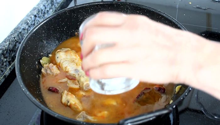 Agregar el agua y el caldo: Incorporar un vaso de agua (y luego los cuatro vasos restantes para completar cinco por cada vaso de arroz). Añadir la media pastilla de caldo. Agregar las alcachofas.