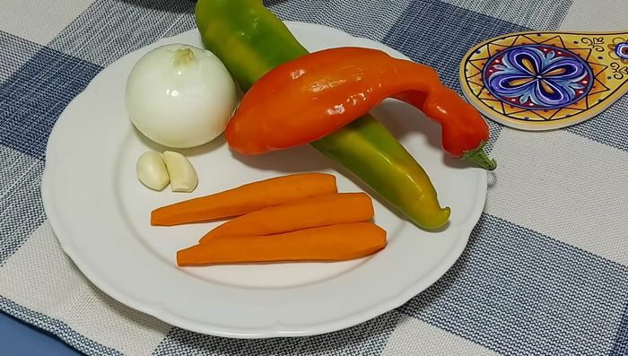 Picar la cebolla, los ajos, los pimientos, las zanahorias y las hojas de laurel.