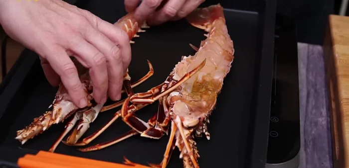 Partir la langosta por la mitad y colocarla en una bandeja de horno. Salpimentar y echar un chorrito de aceite de oliva virgen extra.