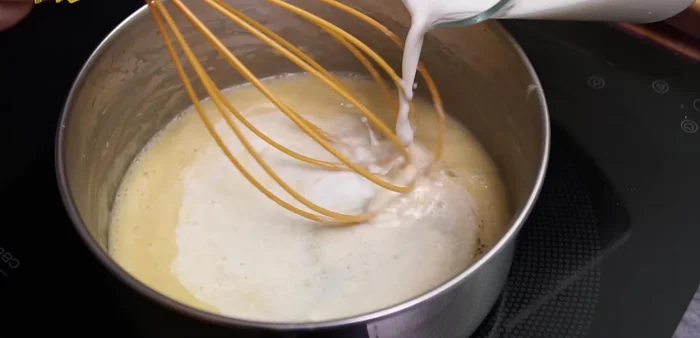 Verter 250ml de leche tibia sin dejar de remover. Salpimentar y seguir batiendo.