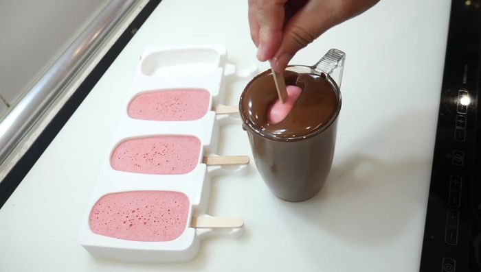 Bañar los helados en el chocolate fundido.