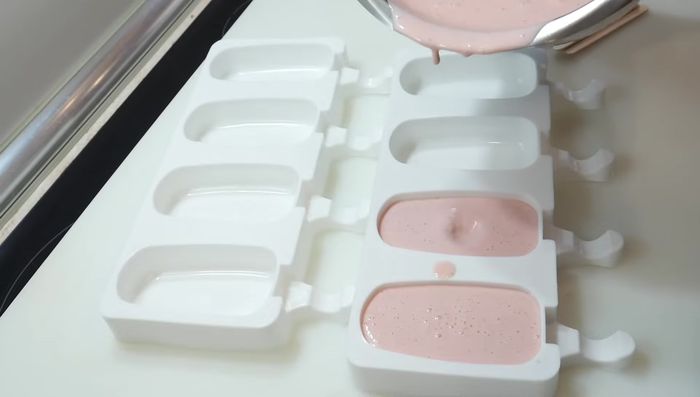 Verter la mezcla en los moldes para helados e insertar los palillos.