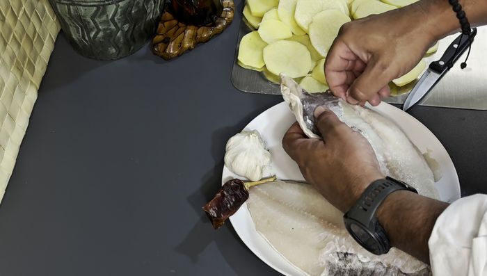 Retirar cualquier espina que pueda quedar en los lomos de bacalao, aunque el pescadero ya los haya limpiado. Cortar los lomos longitudinalmente para facilitar la eliminación de espinas.