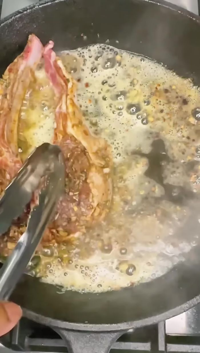 Después de una hora, agregar mantequilla, ajo y romero a las costillas.