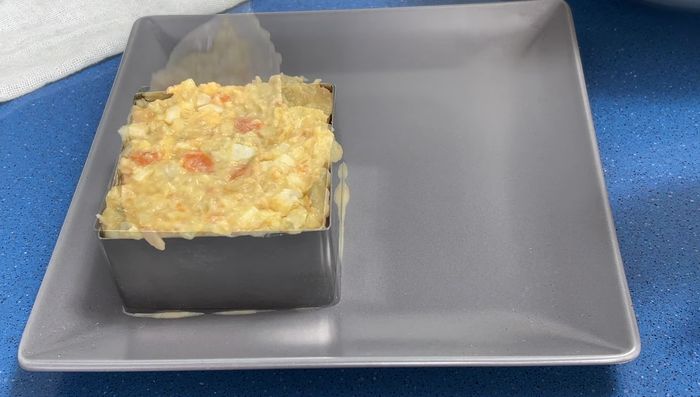 Decorar la ensaladilla: colocarla en un molde cuadrado, aplastar ligeramente. Decorar con huevo rallado, perejil y mejillones.