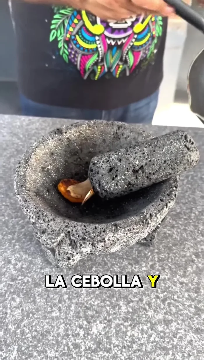 Moler (o molcajetear) los chiles habaneros asados, la cebolla y el ajo.