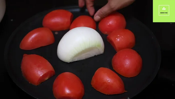 Tatemar la cebolla y los tomates cortados por la mitad en un comal o sartén.