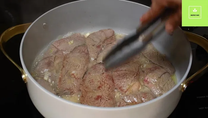 Agregar dos tazas de agua a la carne sellada, junto con una cucharadita de achiote. Mezclar bien.