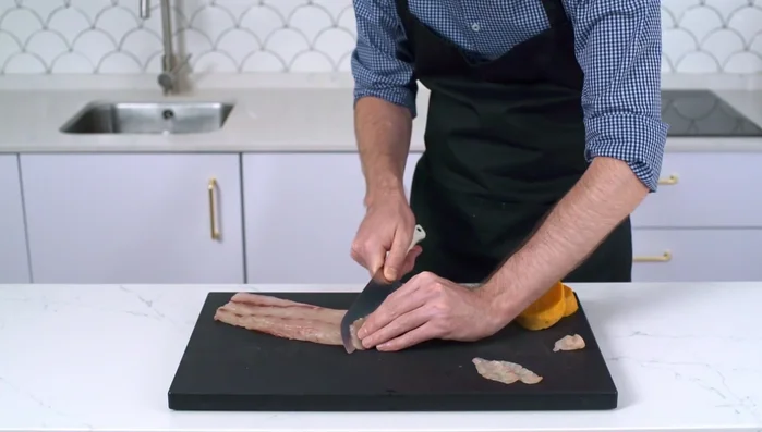 Cortar láminas finas (2 mm de grosor) de corvina en diagonal.