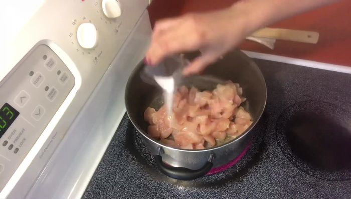 Agregar el pollo a la sartén, sazonar con sal y consomé de pollo. Tapar y cocinar aproximadamente 5 minutos.