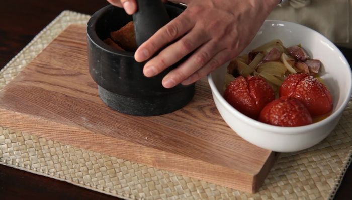 Mientras tanto, preparar la salsa romesco: Machacar en un mortero las avellanas tostadas con el pan frito, la ñora, los ajos asados, los tomates asados y la cebolla. Añadir sal, pimienta, vinagre y emulsionar con aceite y el jugo de las verduras asadas.