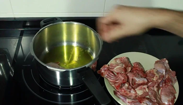 Añadir el conejo a la olla caliente y dorarlo uniformemente por todos lados.
