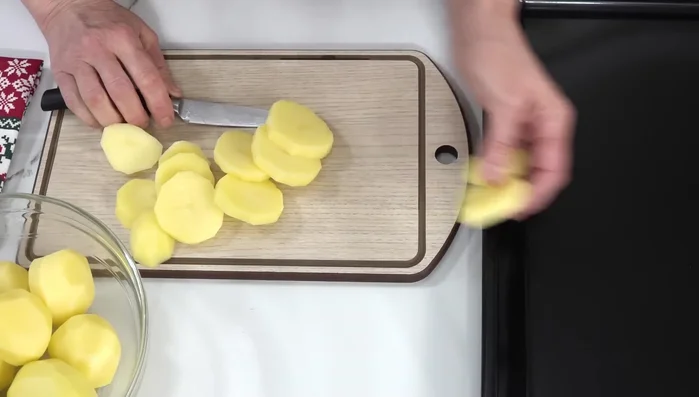 Pelar y cortar las patatas en rodajas de aproximadamente 1 cm de grosor. Colocarlas en una bandeja de horno.