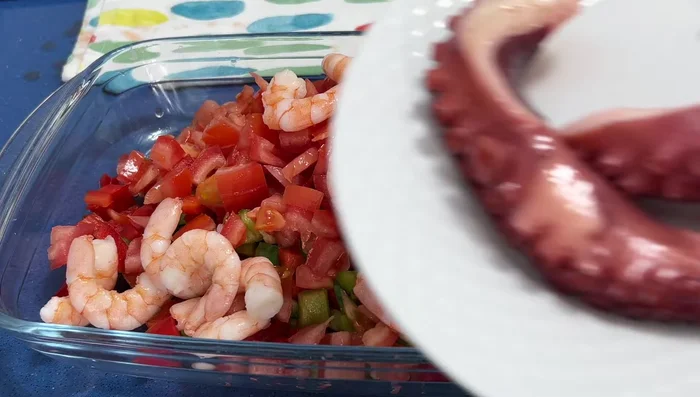 Añadir los langostinos, las patas de pulpo cortadas y los mejillones a una fuente.