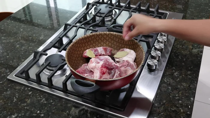 En una cacerola, poner el codillo de cerdo, laurel, cebolla, ajo y sal. Agregar un poco de agua, tapar y cocinar.