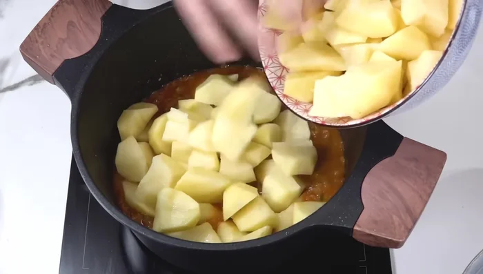 Añadir las patatas al sofrito, junto con la costilla, hojas de laurel y agua hasta cubrir.