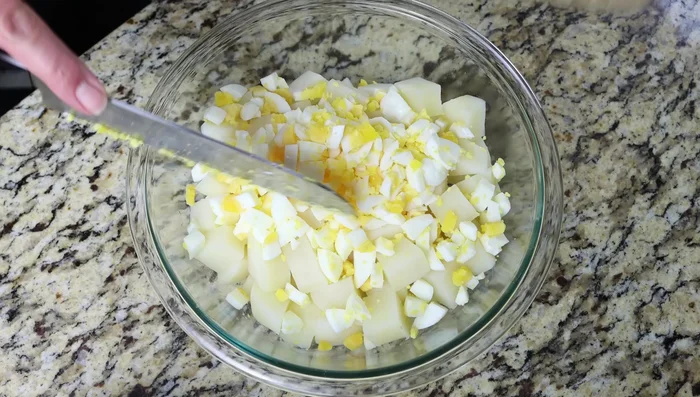 En un bol grande, mezclar las patatas, los huevos duros, la cebolla, los tomates, el maíz y las aceitunas. Sazonar con sal y pimienta.