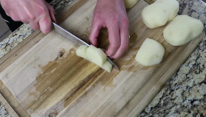 Pelar, lavar y secar las patatas. Cortarlas en trozos pequeños de aproximadamente 1,5 cm.