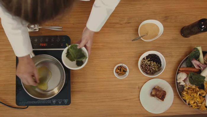 Rehogar espinacas frescas en una sartén con aceite. Agregar la mezcla de alubias, las chantarelas, la mayonesa de ajo y la reducción de huesos de cabrito.