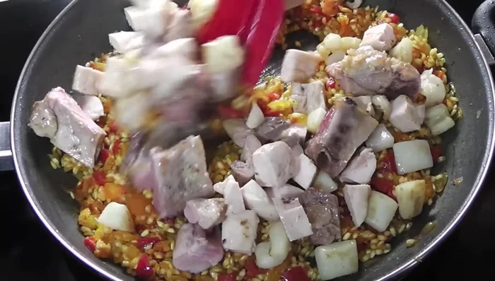 Verter el caldo caliente y cocinar hasta que el arroz esté tierno.
