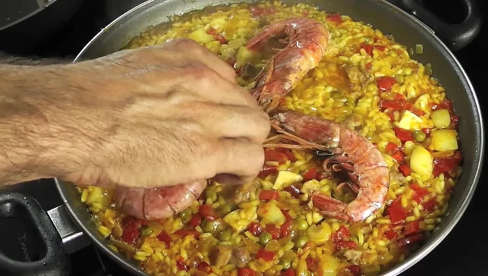 Cuando el arroz esté listo, incorporar las gambas y los mejillones. Retirar del fuego y servir.