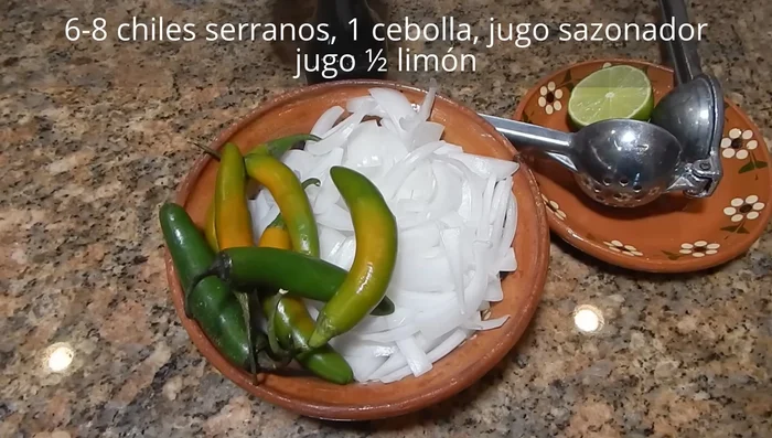 Cocina los chiles toreados: En un sartén con poco aceite, dora los chiles serranos (previamente perforados) y las cebollas fileteadas. Agrega jugo sazonador, limón y sal. (135.59)
