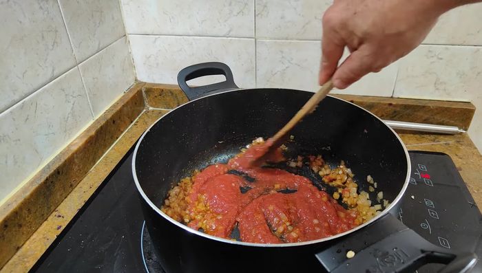 Añadir el tomate triturado y dejar cocer a fuego lento.