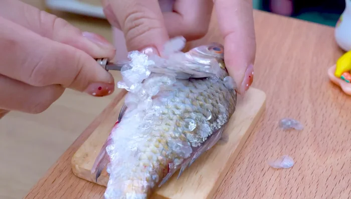 Limpiar el pescado: Limpiar las escamas y cortar la cabeza del pescado. Hacer cortes en el cuerpo del pescado.